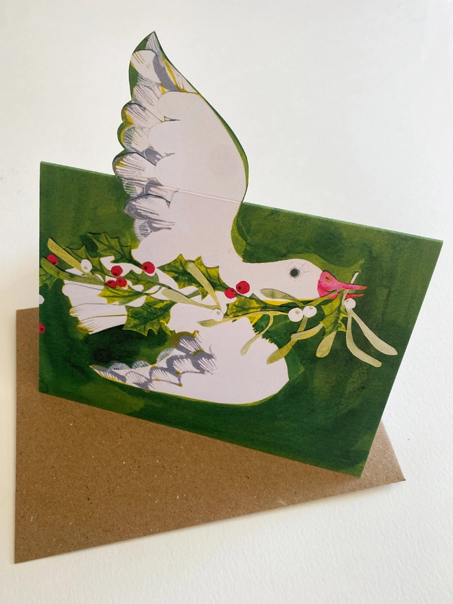 Esther Kent illustrated Christmas Card showing white goose on green inky background, carrying holly and mistletoe