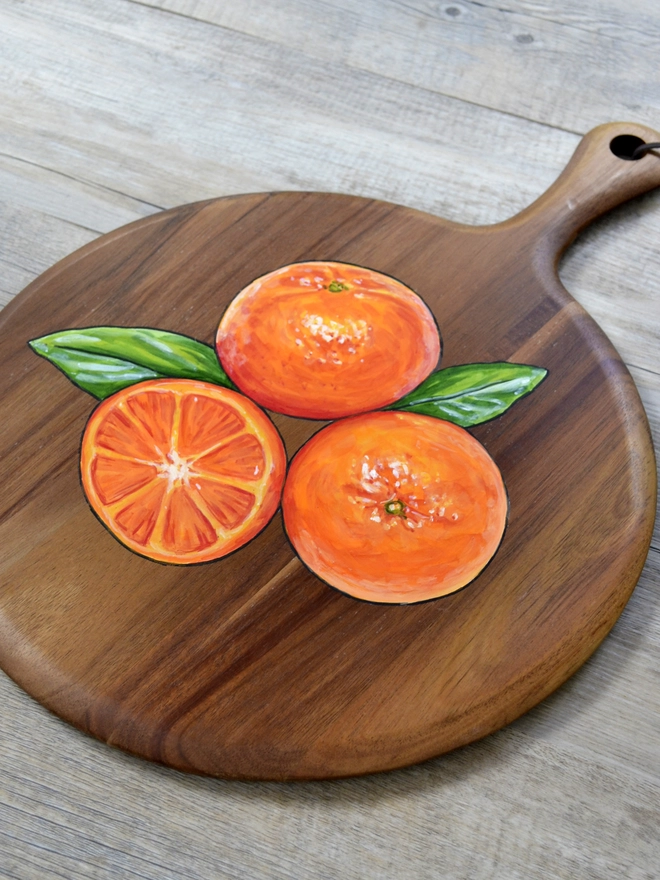 Wooden serving board with a handpainted design of some clementines