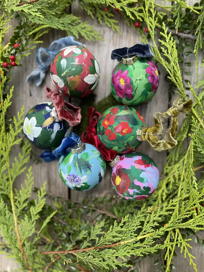 a set of six hand vibrant painted floral ceramic baubles all painted with an array of winter florals each finished with a luxurious velvet ribbon 