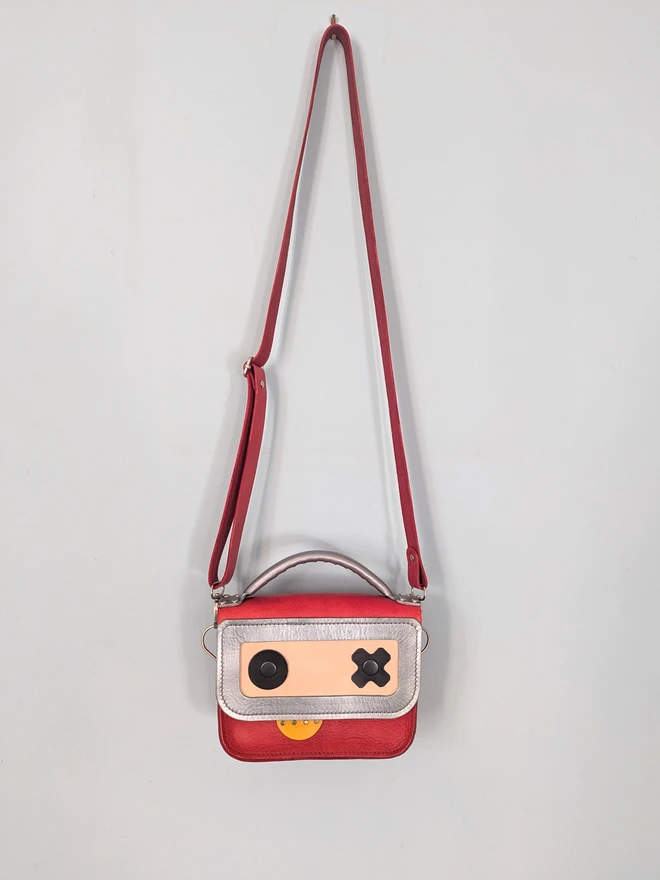 Hanging red leather robot cross body bag, front view.