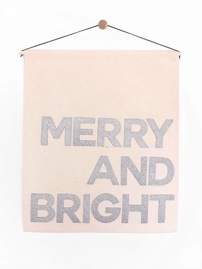 Merry and Bright stitched onto a Christmas wall hanging in a glittery silver
