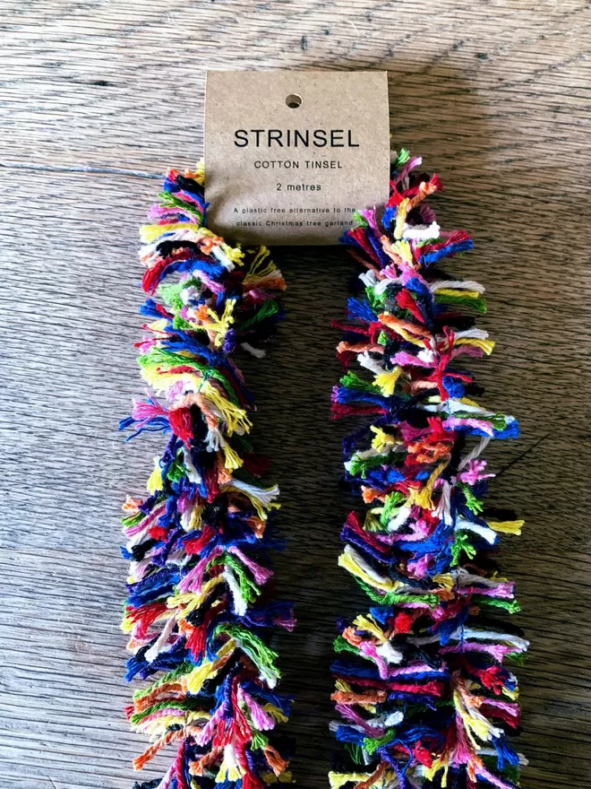 Rainbow cotton string tinsel AKA Strinsel packaged in a kraft card label on an oak table