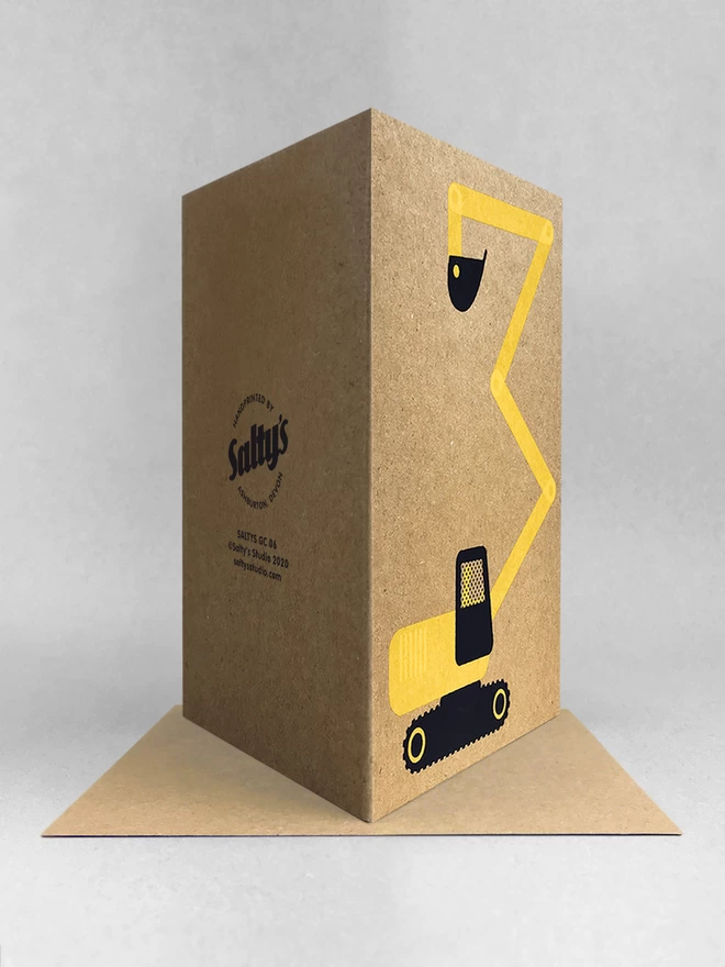 rear view of a brown kraft greetings card with a yellow and black digger stood in a light grey studio background, oft shadows. The digger has been screenprinted in two colours and the arm of the digger makes a number 3.