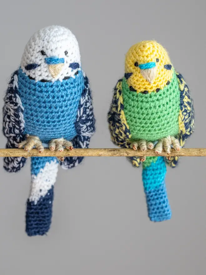 Budgerigar Hand Crocheted Figure, a blue and green crocheted bird sitting on a wooden poll. 