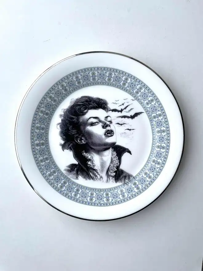 the vampire Lestat wtih bats behind him, the image is victorian in black and white and is printed directly onto an ornate vintage plate