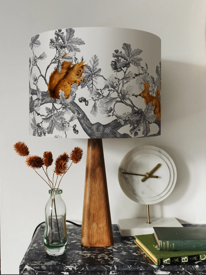 A decorative lampshade featuring red squirrels among oak leaves and acorns, inspired by the British countryside and woodland wildlife.