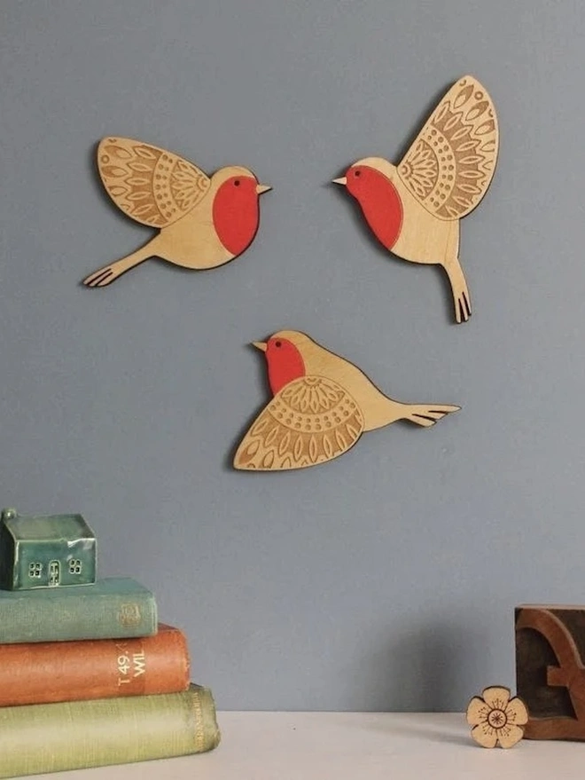 Folk Art Wooden Wall Robins (Set Of 3), a group of wooden robins flying hung up on a wall. 