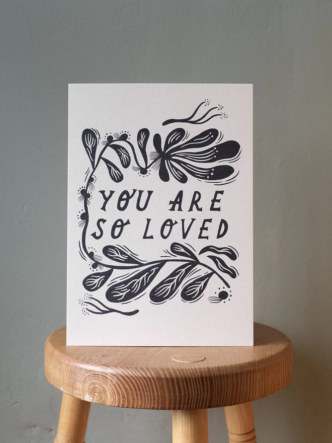 'You Are Loved' black and white art print with lino cut style botanical border