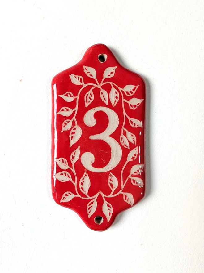 Red Sgraffito Leaf Address Tile. A tile with ‘3’.