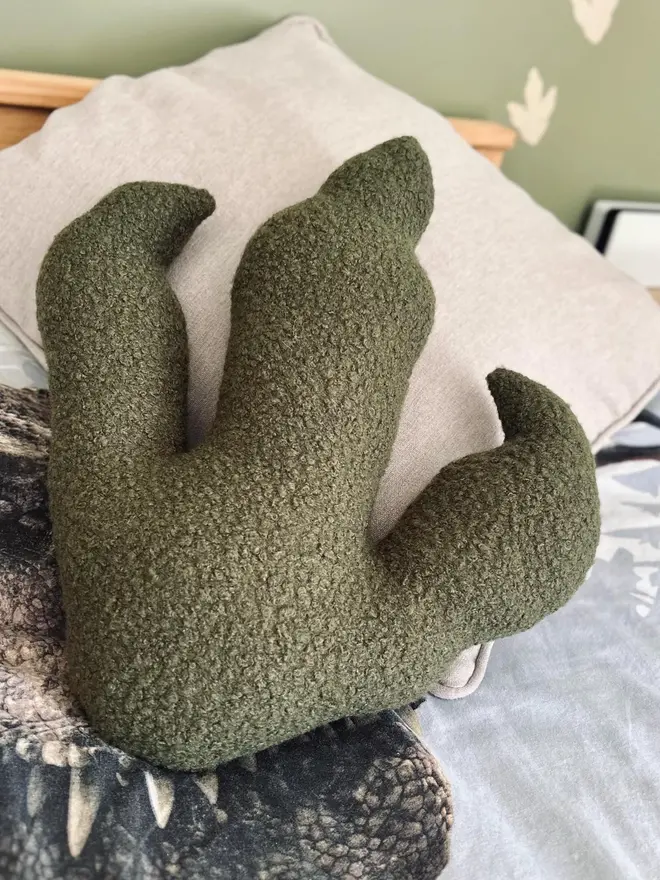boucle dinosaur footprint cushion. a green dinosaur foot cushion.