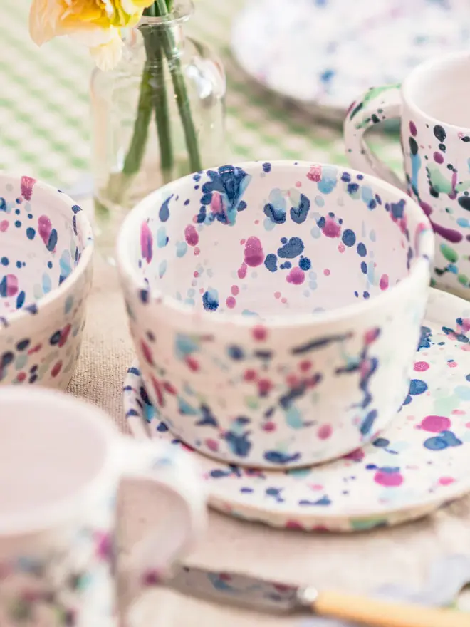 Sweetpea Breakfast Dishes (Set Of 2), colourful breakfast dishes placed on a colourful table setting. They are accompanied by flowers, napkins and other cutlery. 