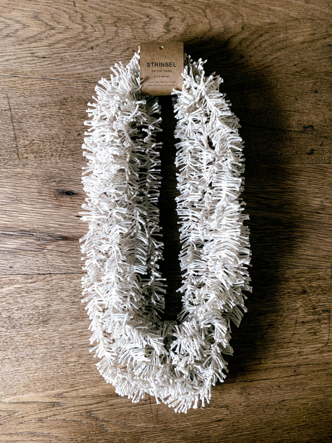 Multipack of white Plain Cotton Strinsel (plastic free string tinsel) on an oak background