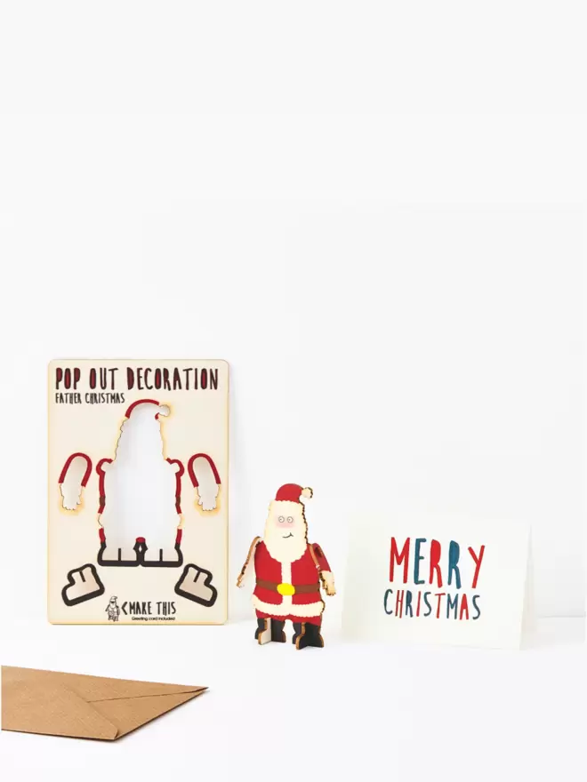 Pop out Father Christmas decoration and Merry Christmas card and brown kraft envelope on a white background