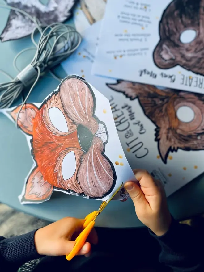 Cut And Create Forest Animals Children’s Masks, a child cutting out a paper fox mask from a "Cut and Create" woodland animal craft kit.