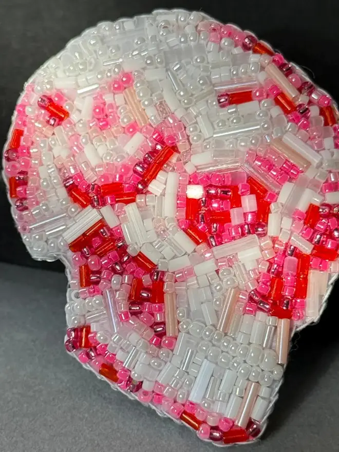 Beaded Pink Skull Brooch, against a grey background. 