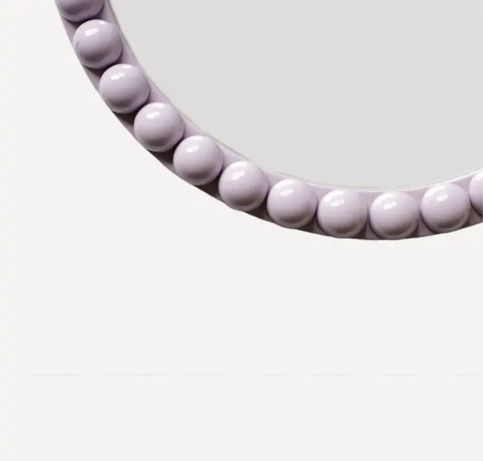 Round oversized bobbin mirror with a decorative bobbin-style wooden frame, hanging on a white wall.