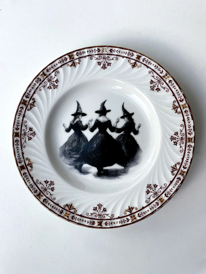 a vintage plate with an ornate floral border in the centre is a witch's coven