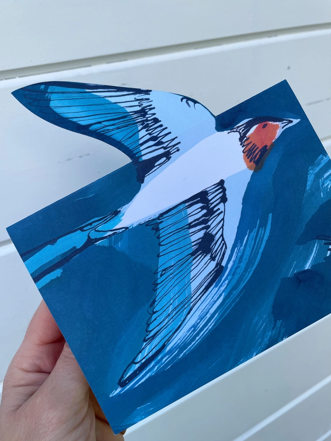 Esther Kent illustrated greeting card showing inky blue swallow illustration on a teal background. The swallow's wing pops u.