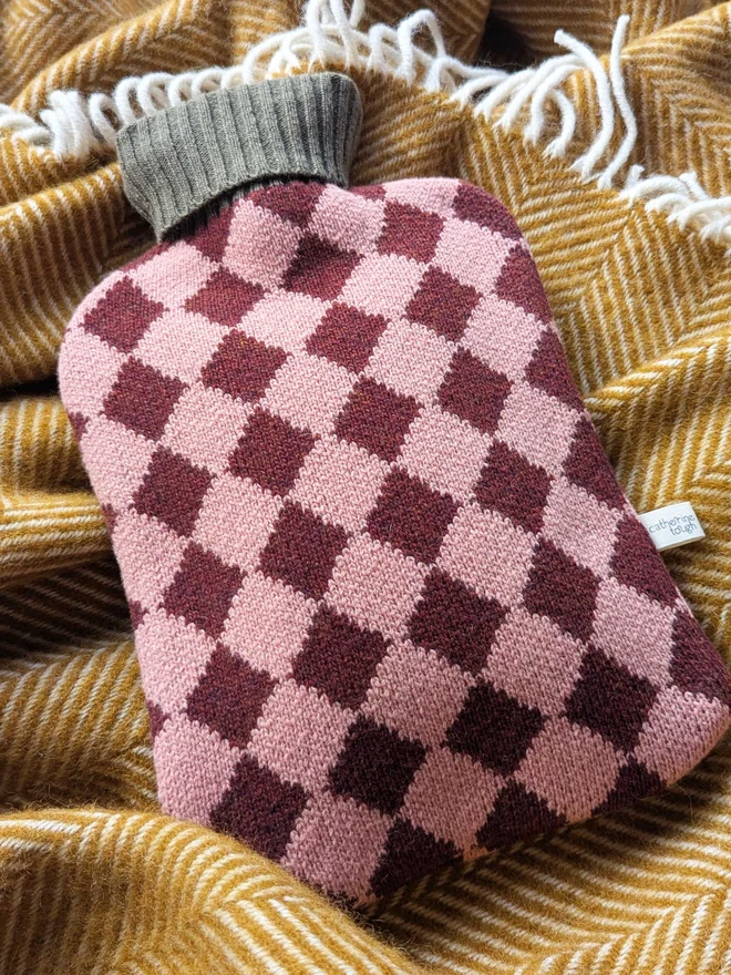 COLOURFUL HOT WATER BOTTLE COVER DISPLAYED ON A ON A BLANKET