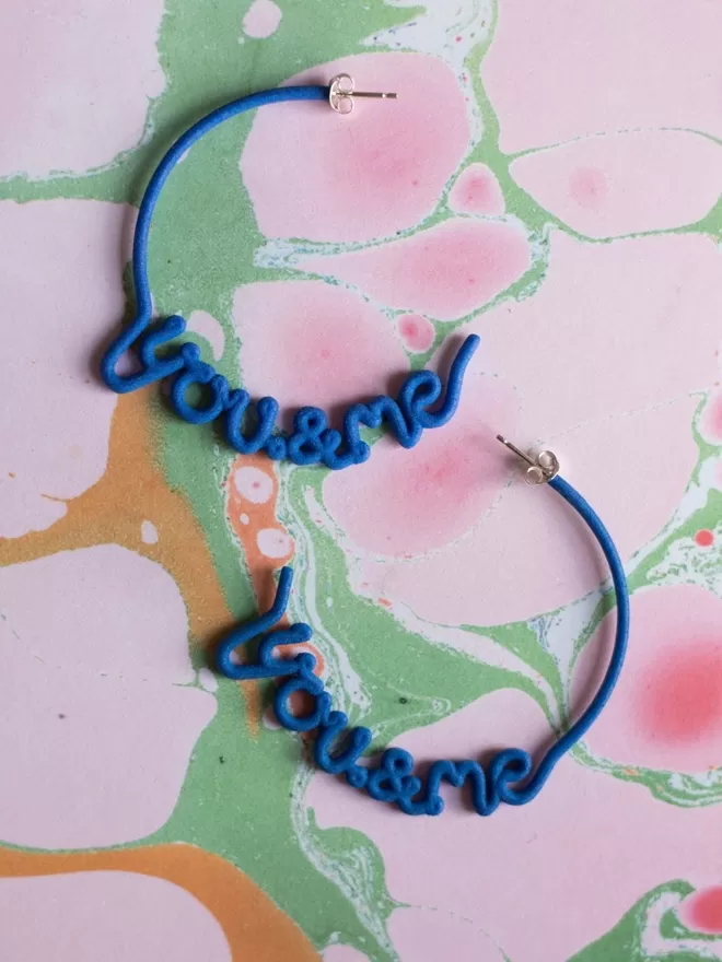 You & Me hoops by Zoe Sherwood in blue seen on a marble.