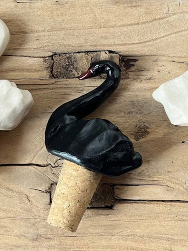 black swan shaped bottle stopper lying on wooden table