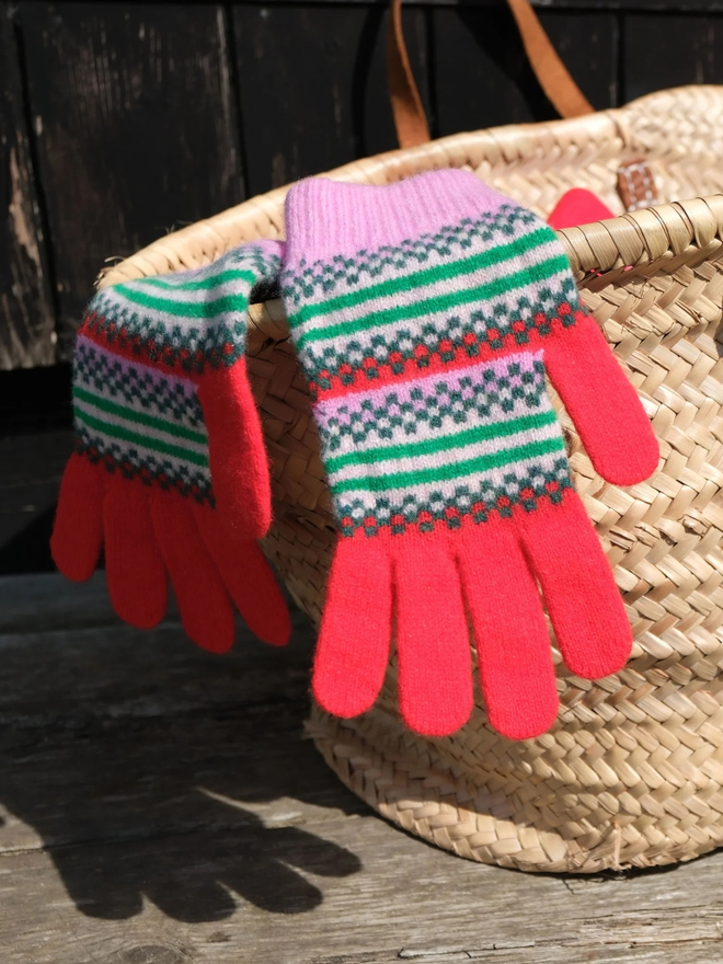 Red fairisle gloves. Red fairisle with a pink trim on top of a wicker basket