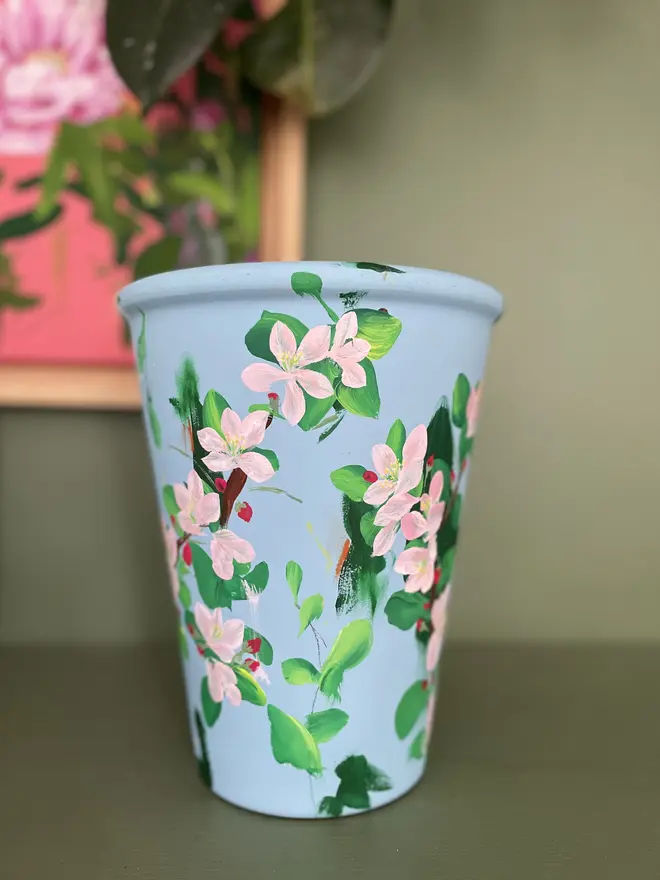 hand painted floral terracotta interior plant pot pale blue background pink apple blossom flowers