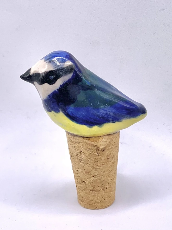 Blue Tit Ceramic Bird Bottle Stop, a bird themed bottle stop sitting on a wine bottle outside
