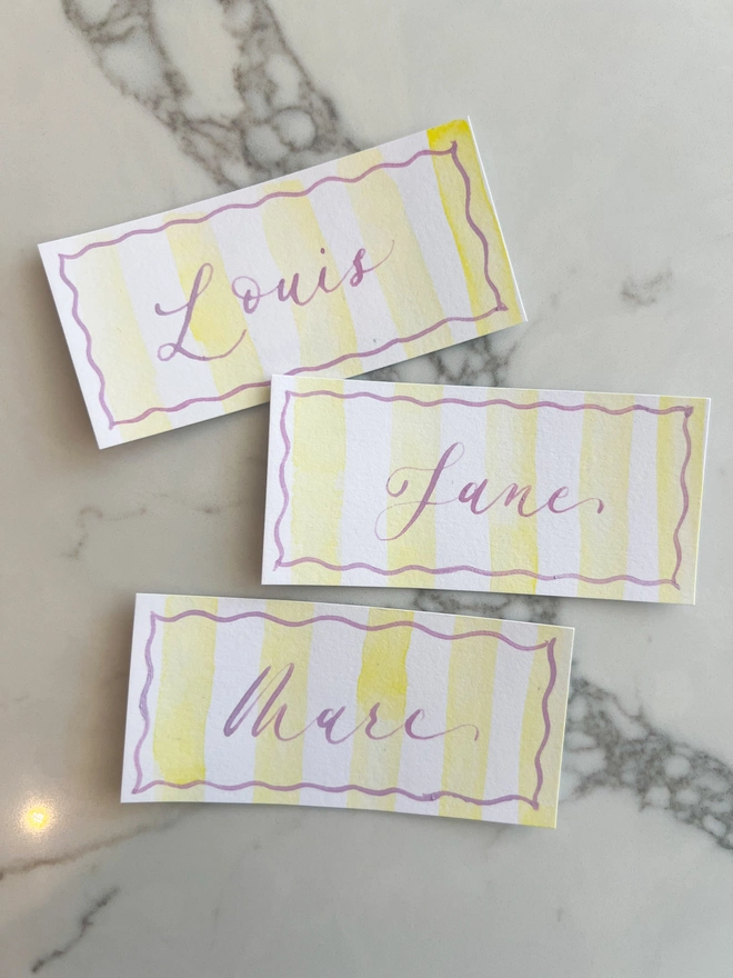 Personalised calligraphy event place cards, yellow striped place cards with french lavender calligraphy name
