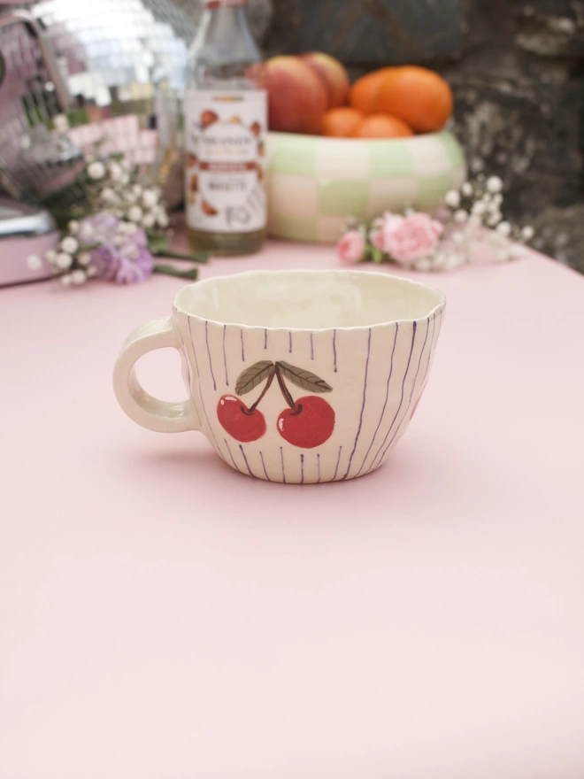handmade stoneware pottery mug decorated with purple stripes and handpainted cherries