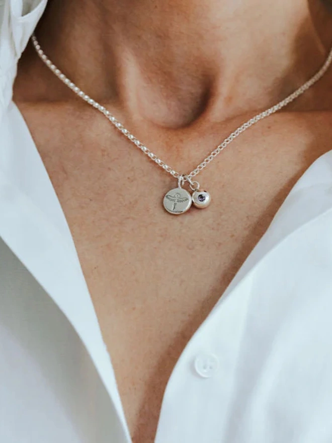 A woman wearing a Sterling silver Phoenix Pebble Necklace with a birthstone charm