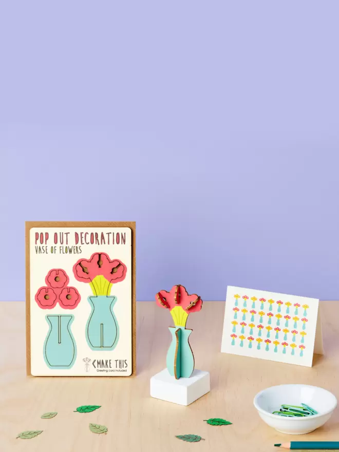 Vase of flowers 3D decoration and vase of flowers pattern greeting card and brown kraft envelope on top of wooden desk with lilac-coloured background