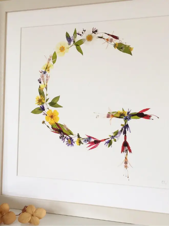 Pressed Wildflower Letter Print, a wildflower alphabet letter print sitting framed. 