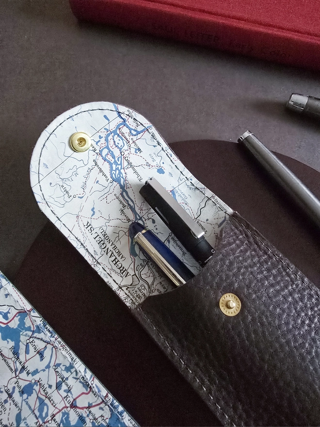 detail of a brown leather pencil case lined with a silk escape map