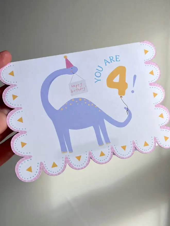 illustrated dinosaur 4th birthday card. scallop edged card with illustrated purple dinosaur.