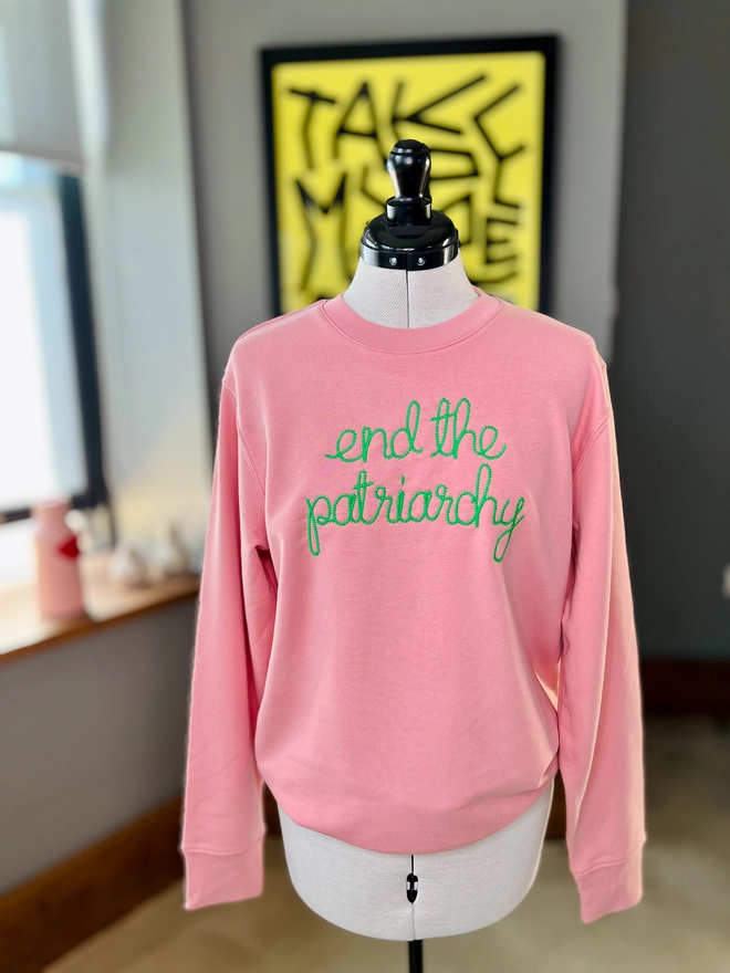 A pink sweatshirt on a dressmakers dummy embroidered with end the patriarchy