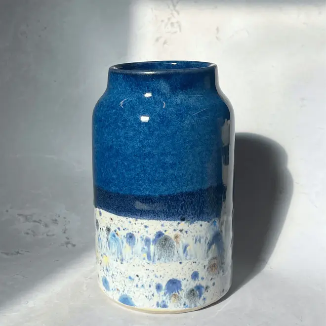 Shoreline Large Vase, a colourful vase placed on a stone surface in front of a plain backdrop. 