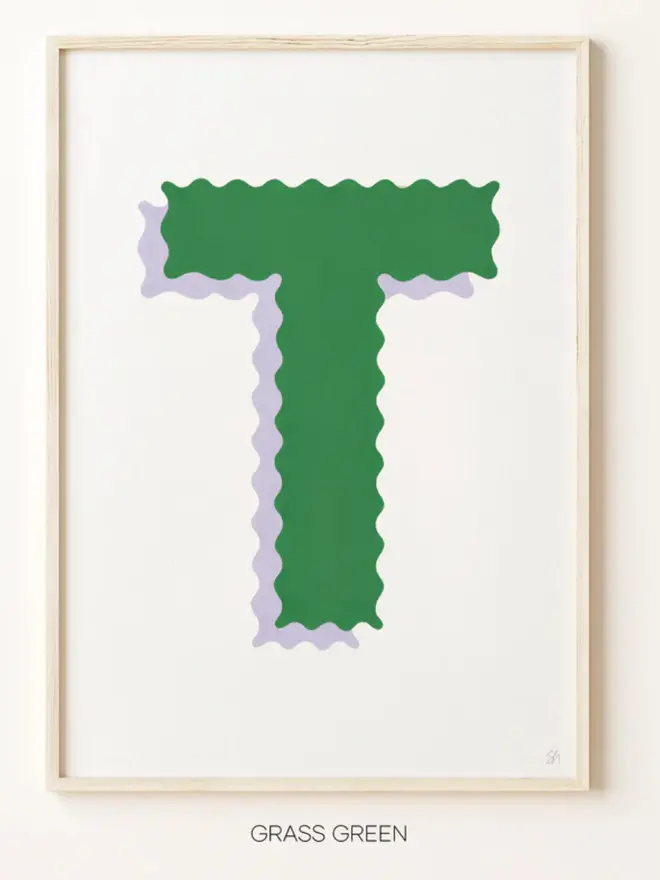 Framed wall art print featuring a large decorative letter “T” in soft green tones with a ric rac–style wavy edge design, centered on a white background. 