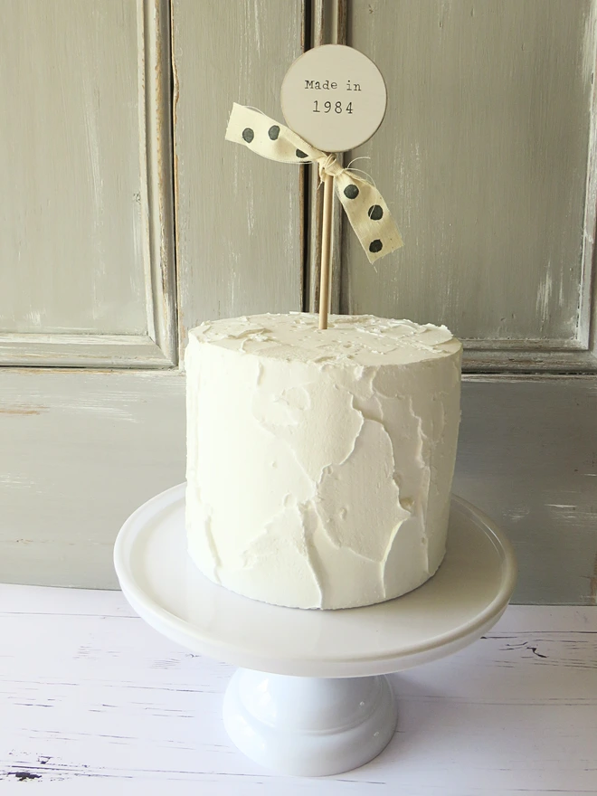 wooden circle shaped cake topper with hand painted message and custom ribbon