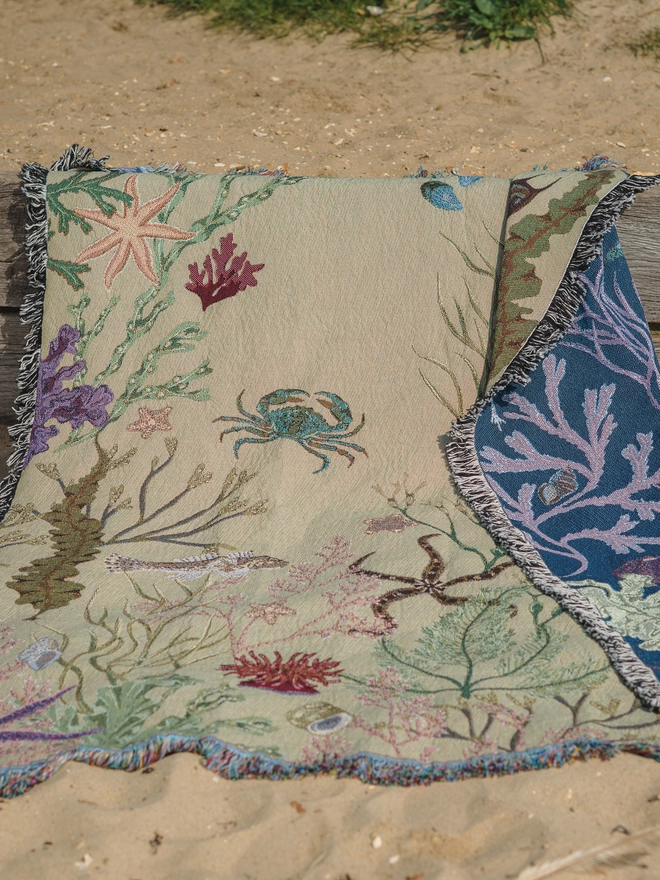 'Intertidal Sand' Recycled Cotton Blanket seen on the beach.