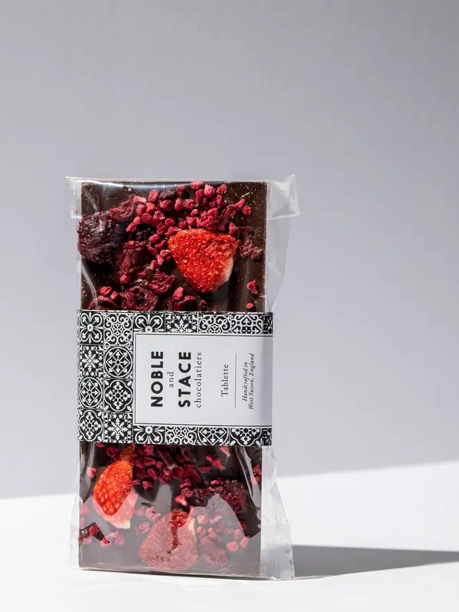 Very berry 70% chocolate tablette wrapped in clear plastic and standing on a white table. 