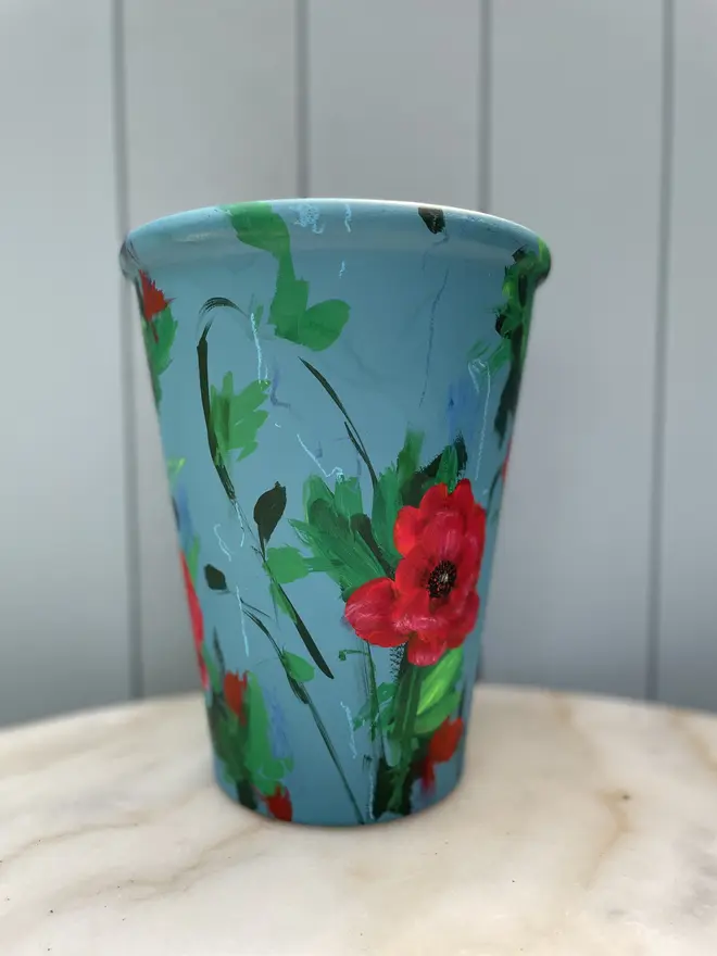 Unique hand-painted terracotta pot featuring red poppies on a royal blue background