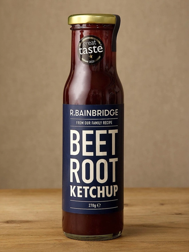 Beetroot Ketchup, the jar of ketchup sitting on a wooden surface in front of a plain backdrop. 