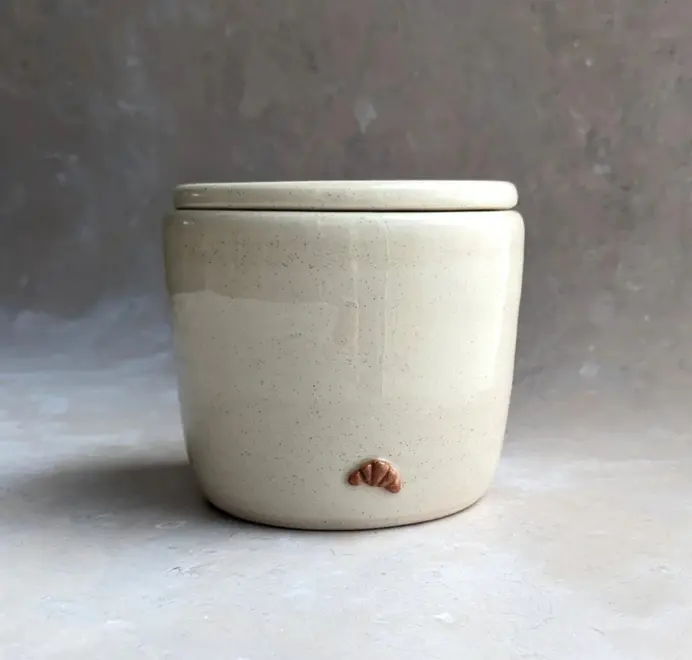 Croissant Butter Crock in vanilla bean glaze with a small croissant design on the front, set against a clean white marble background.