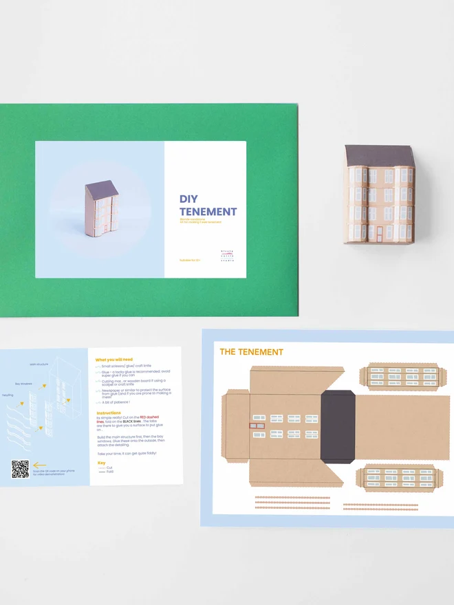 A photo of the elements of the DIY kits laid flat including - instructions, cut out sheet, a bothy made of a paper, an envelope with a label saying it is a DIY kit. 