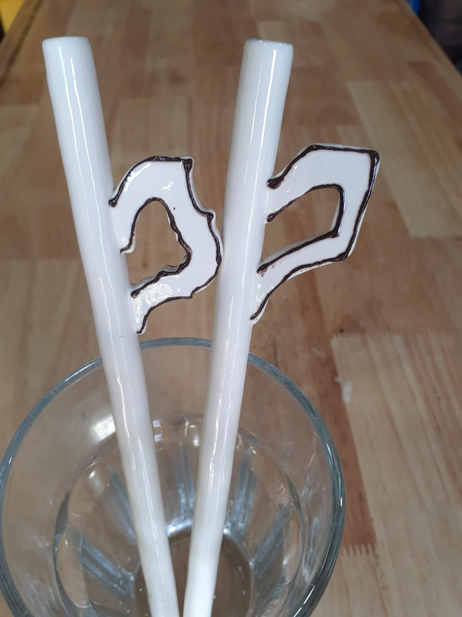 Close-up of artisan ceramic straws with sculptural teacup handle details and glossy glaze finish