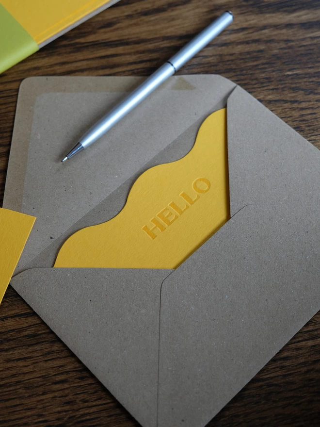 Wavy yellow 'Hello' notecard in Kraft envelope.