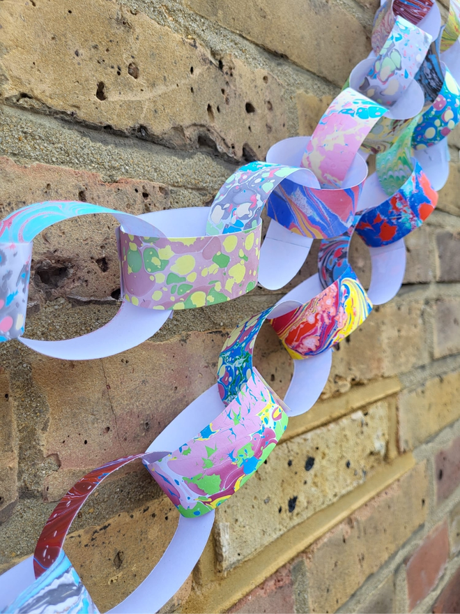 hand marbled multi colour paper chain hanging on brick wall