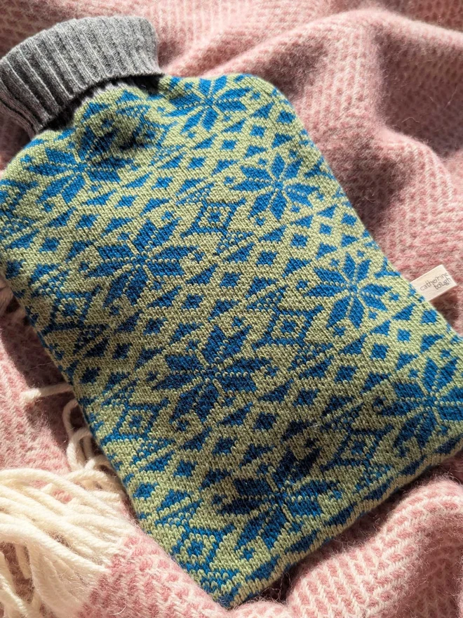 COLOURFUL HOT WATER BOTTLE COVER DISPLAYED ON A ON A BLANKET