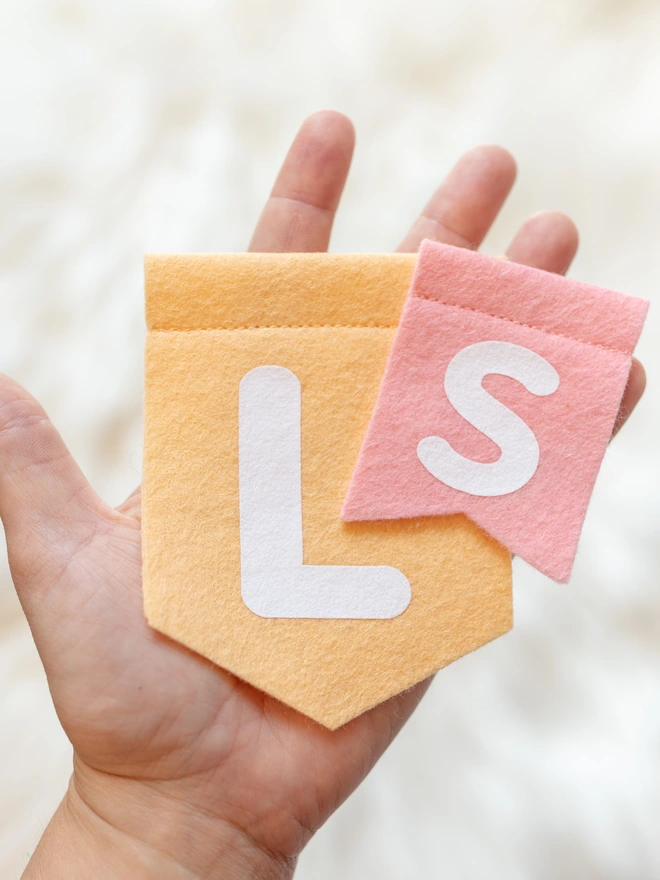 a hand holding 2 felt flags, showing the size difference between small and large.